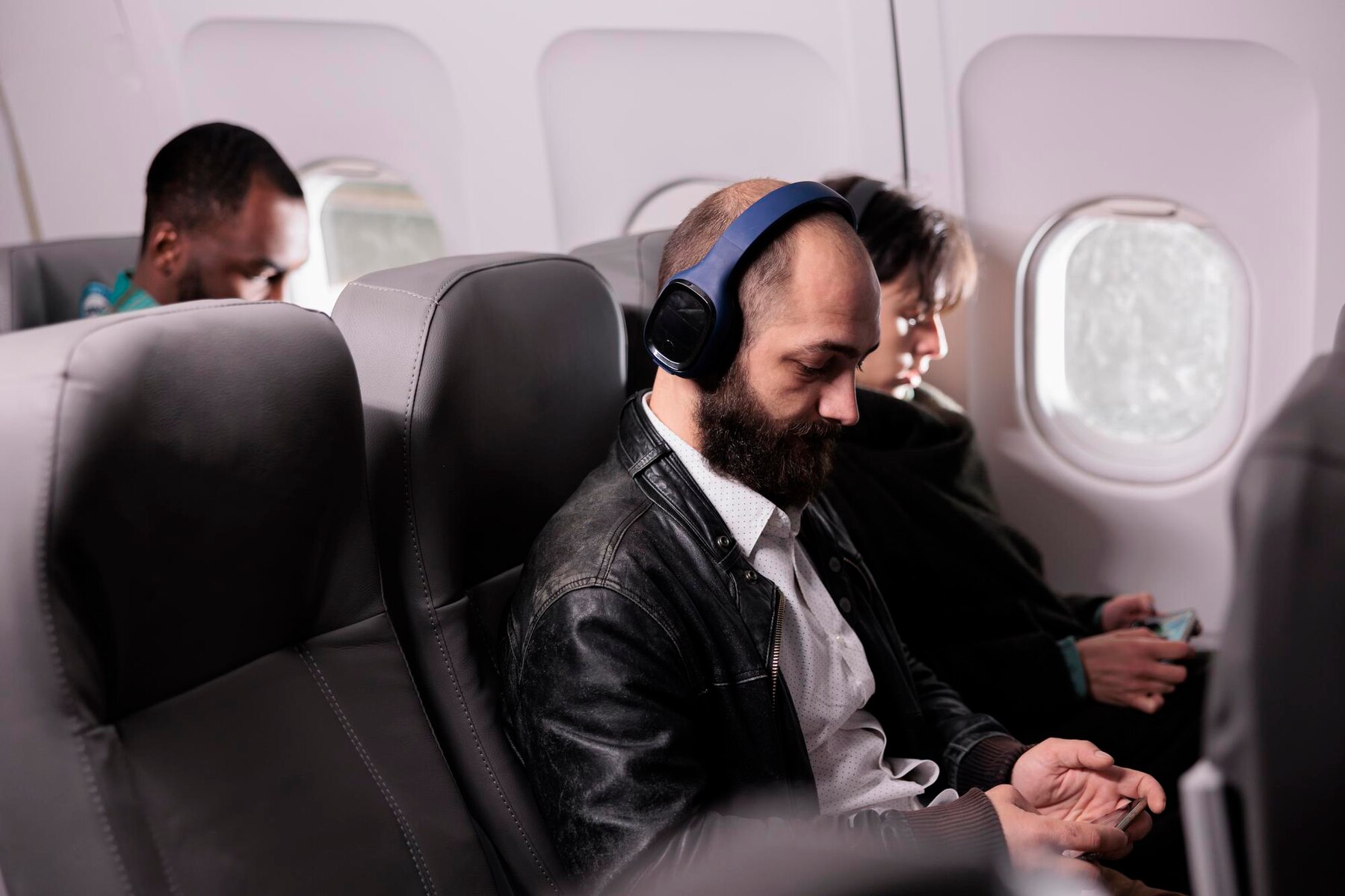 Čeovek nosi slušalice dok sedi u avionu