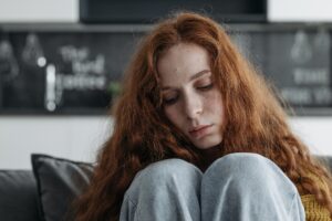 Usamljena žena sedi na krevetu i nije raspoložena jer ima zujanje u ušima