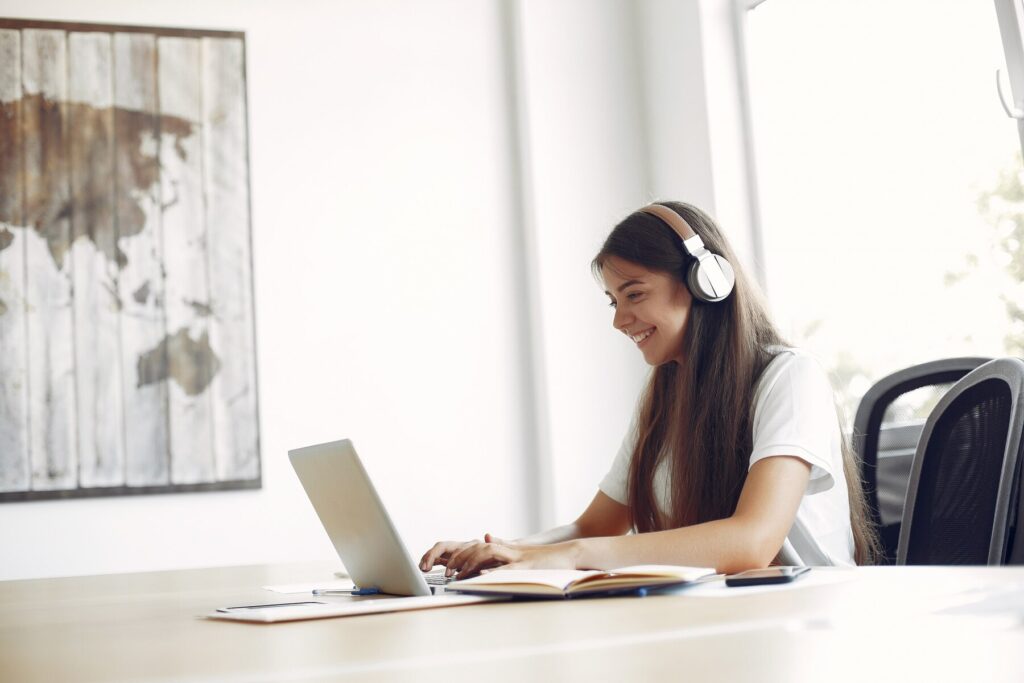 Studentkinja koja radi na računaru i nosi slušalice